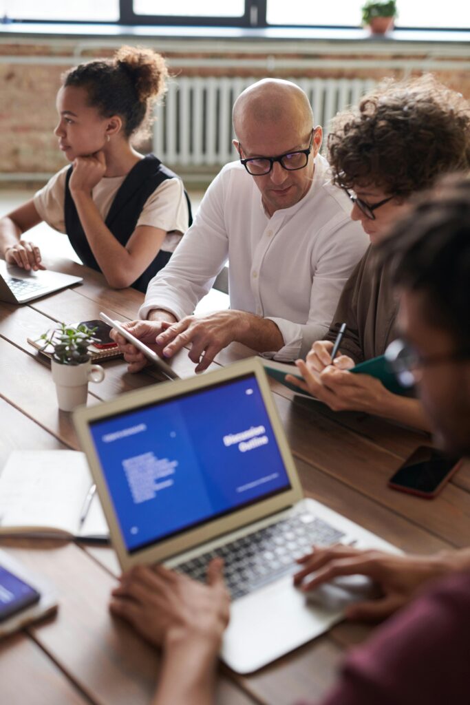 pexels-photo-3184162-3184162 Diverse team engaged in a collaborative business meeting around a wooden table with laptops.
